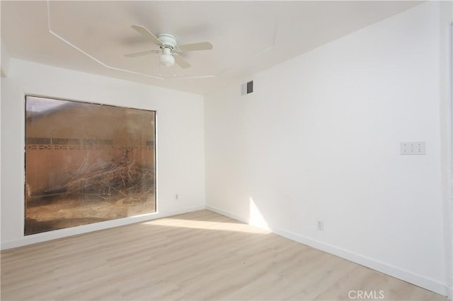 empty room with a ceiling fan, wood finished floors, visible vents, and baseboards