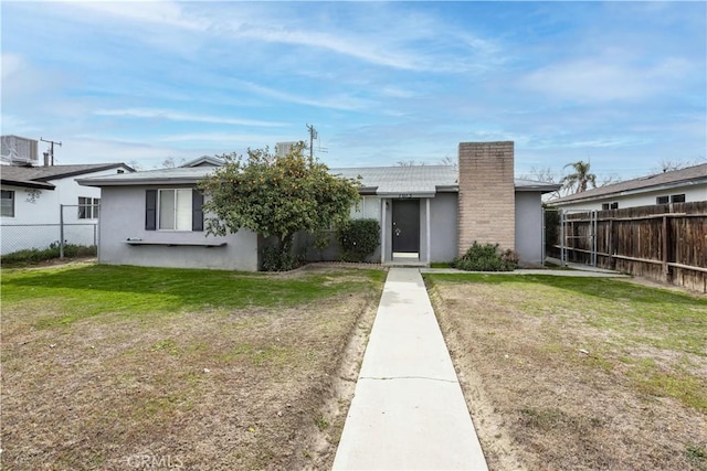 view of front of property featuring a chimney, a front yard, fence, and stucco siding