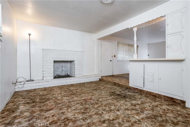 unfurnished living room with a brick fireplace and carpet