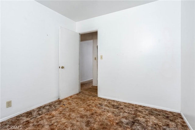 carpeted spare room featuring baseboards