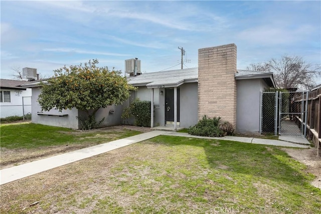 view of front of house with stucco siding, a gate, fence, cooling unit, and a front lawn