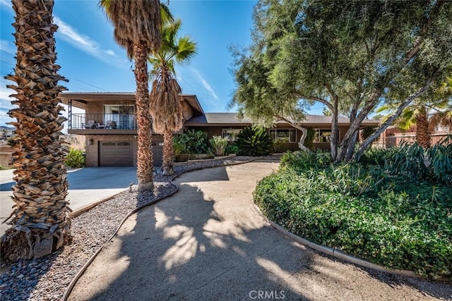 view of front of house featuring driveway, an attached garage, and a balcony