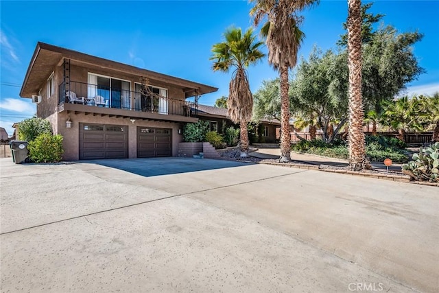 view of front of home with a garage, driveway, a balcony, and stucco siding