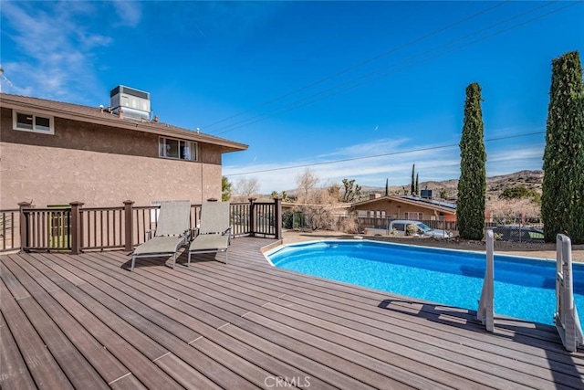 view of swimming pool with central AC unit, fence, a deck, and a fenced in pool