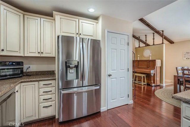 kitchen with dark wood-type flooring, cream cabinetry, stainless steel fridge, and a toaster