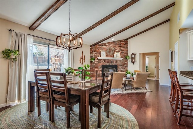 dining space with a notable chandelier, vaulted ceiling with beams, dark wood-type flooring, a brick fireplace, and baseboards