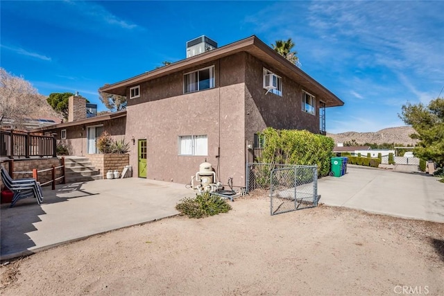 rear view of property featuring a mountain view, a patio, fence, and stucco siding