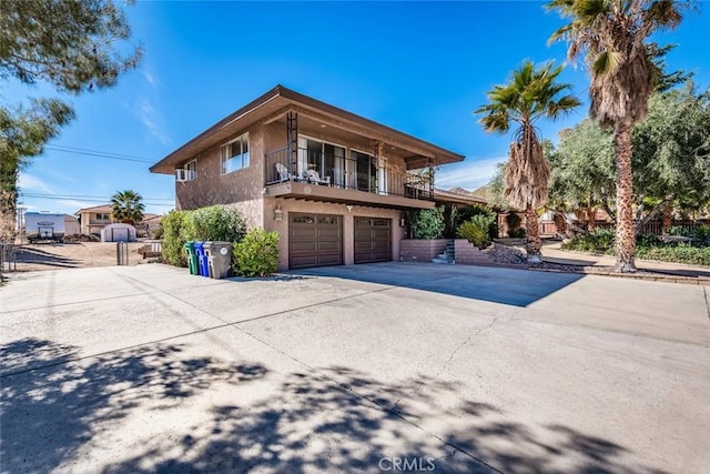 view of home's exterior with driveway, a balcony, an attached garage, and stucco siding