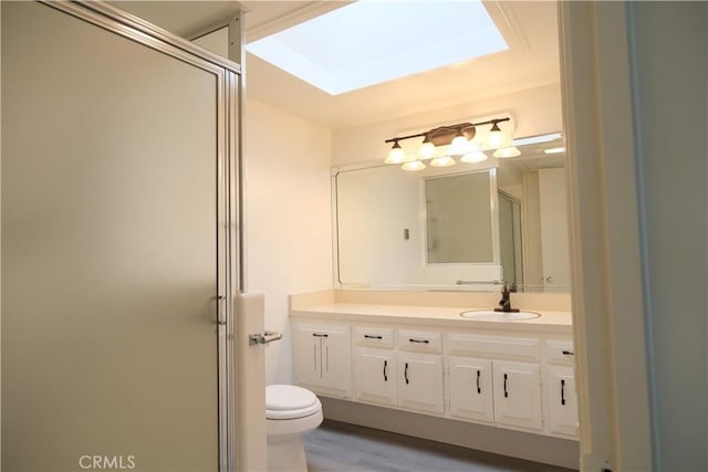 bathroom with toilet, a stall shower, wood finished floors, and vanity