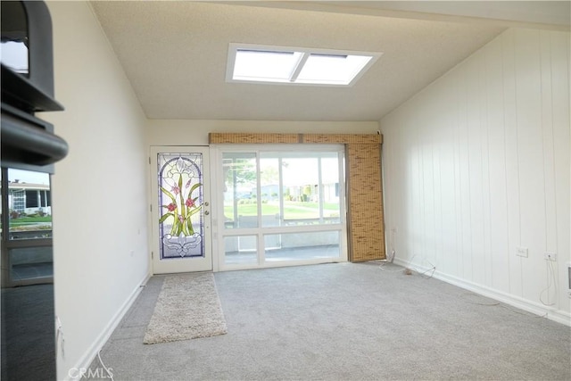 interior space featuring carpet, vaulted ceiling with skylight, and baseboards