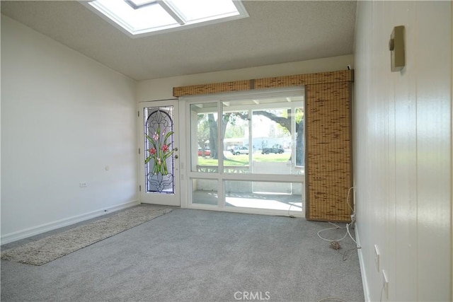 entryway featuring carpet floors, lofted ceiling with skylight, and baseboards