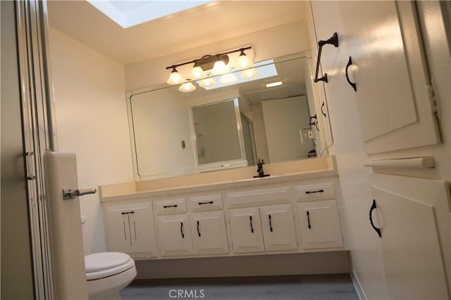 bathroom with a skylight, vanity, and toilet