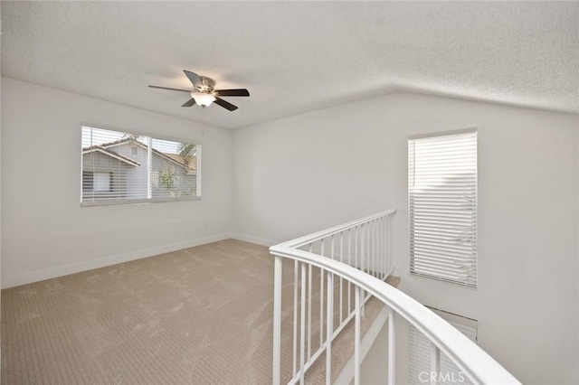 interior space featuring baseboards, a ceiling fan, lofted ceiling, a textured ceiling, and carpet floors