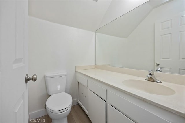 bathroom with vaulted ceiling, vanity, toilet, and wood finished floors