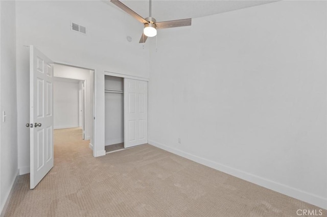 unfurnished bedroom with a closet, light colored carpet, visible vents, and baseboards