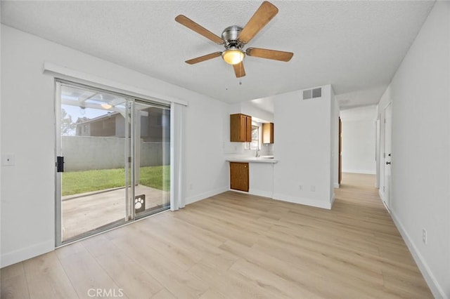 unfurnished living room featuring light wood-style floors, visible vents, and baseboards