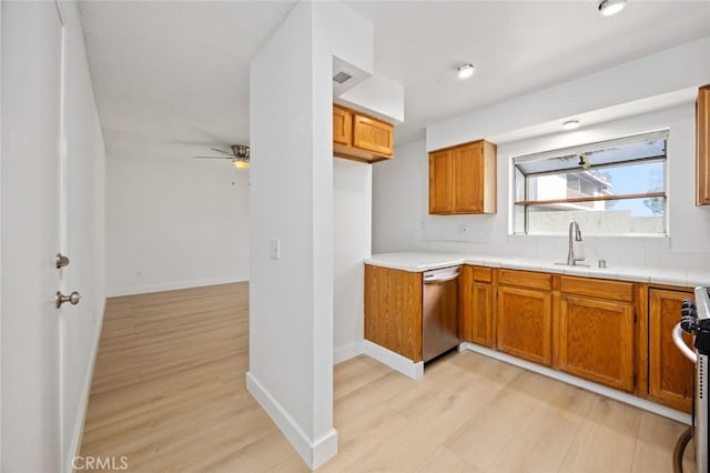 kitchen featuring stainless steel appliances, a sink, light wood-style flooring, and brown cabinets