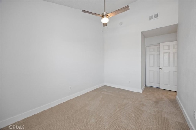 carpeted spare room featuring a ceiling fan, visible vents, and baseboards