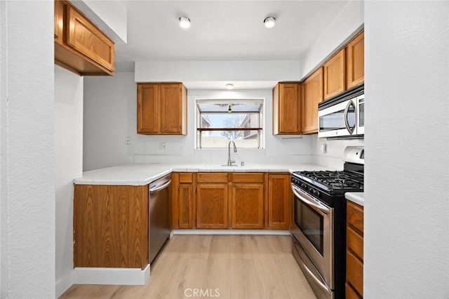 kitchen with stainless steel appliances, brown cabinets, and a sink