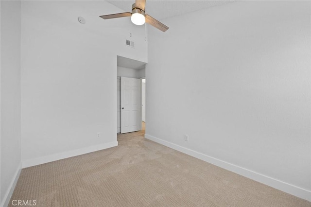 empty room featuring light colored carpet, visible vents, a ceiling fan, high vaulted ceiling, and baseboards