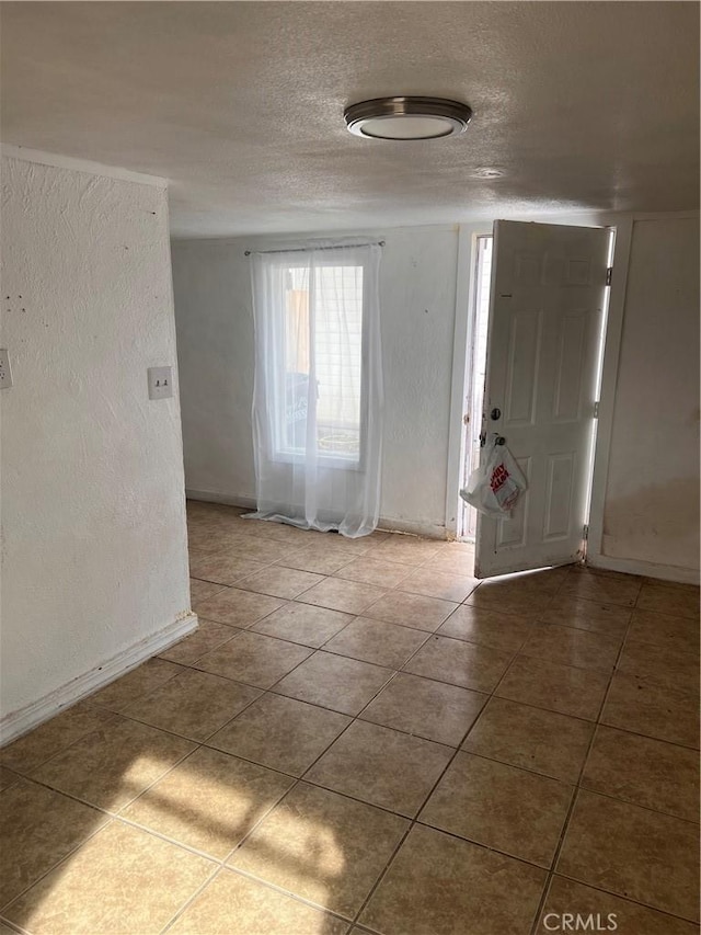 entrance foyer with tile patterned flooring, a textured wall, and a textured ceiling