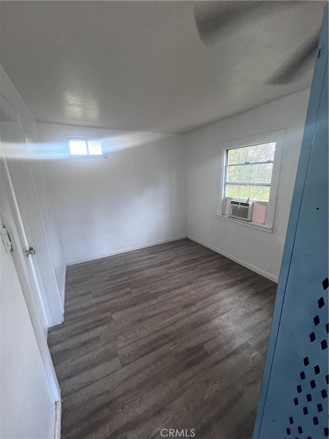 unfurnished room featuring dark wood-type flooring, cooling unit, and baseboards