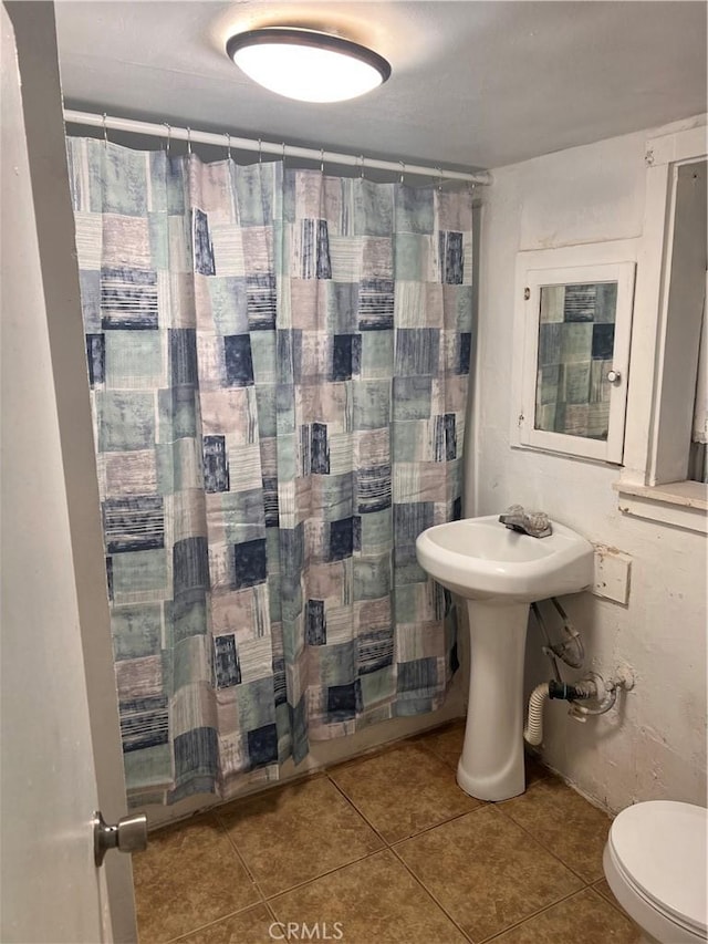 bathroom featuring a shower with curtain, toilet, and tile patterned floors