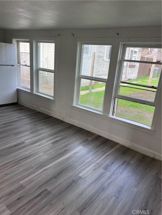 interior space featuring a textured ceiling, wood finished floors, and baseboards