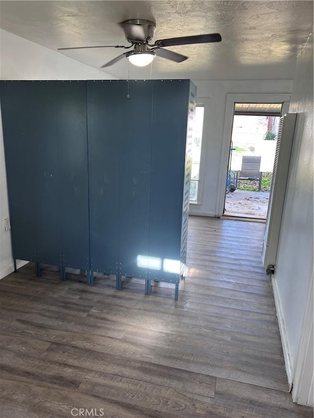 unfurnished room with dark wood-type flooring, ceiling fan, a textured ceiling, and baseboards