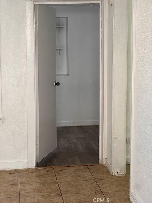 corridor featuring tile patterned flooring and baseboards