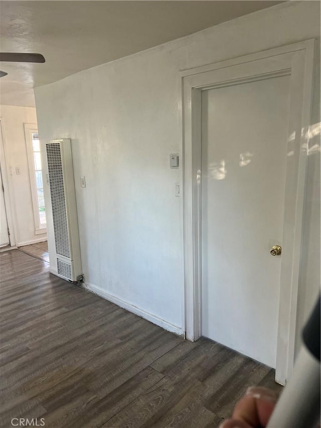 empty room featuring dark wood-style flooring, a heating unit, and ceiling fan