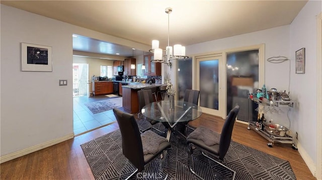 dining space with baseboards, a chandelier, and wood finished floors