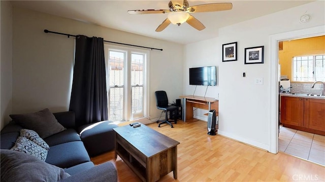 living area featuring a ceiling fan, a healthy amount of sunlight, and light wood-style flooring