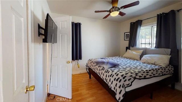 bedroom featuring a ceiling fan, baseboards, and light wood finished floors