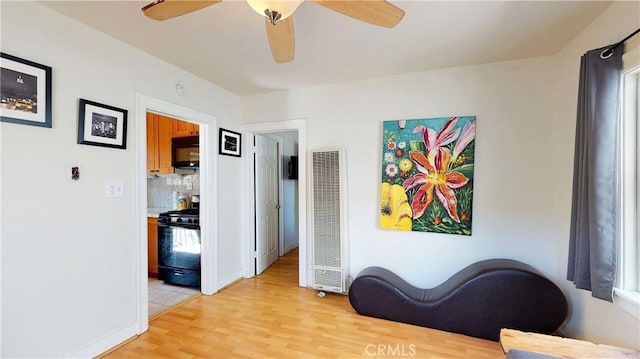 living area featuring light wood-type flooring, ceiling fan, and a heating unit