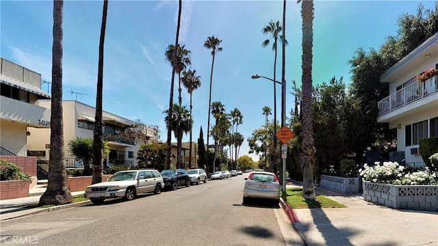 view of road featuring sidewalks, curbs, a residential view, street lighting, and traffic signs