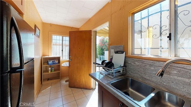 kitchen with freestanding refrigerator, a sink, and light tile patterned floors