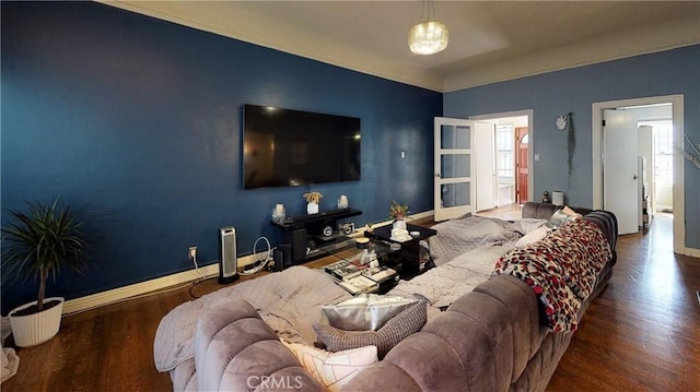 living area with an accent wall, baseboards, and wood finished floors