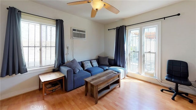 living room with an AC wall unit, a healthy amount of sunlight, and wood finished floors