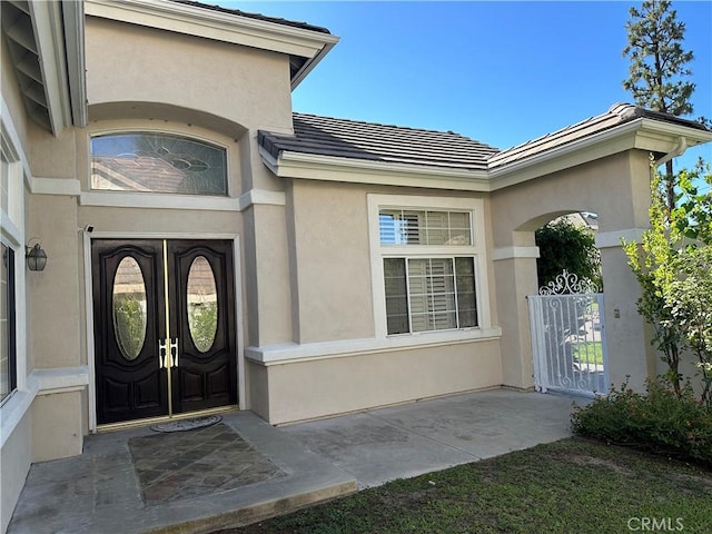 view of exterior entry featuring a tiled roof and stucco siding