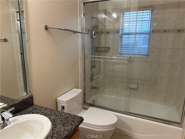 full bathroom featuring toilet, a textured wall, combined bath / shower with glass door, and vanity