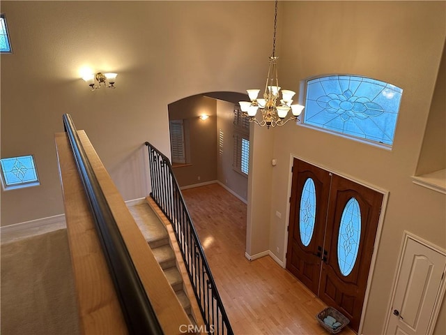 foyer entrance featuring a towering ceiling, stairs, arched walkways, and wood finished floors