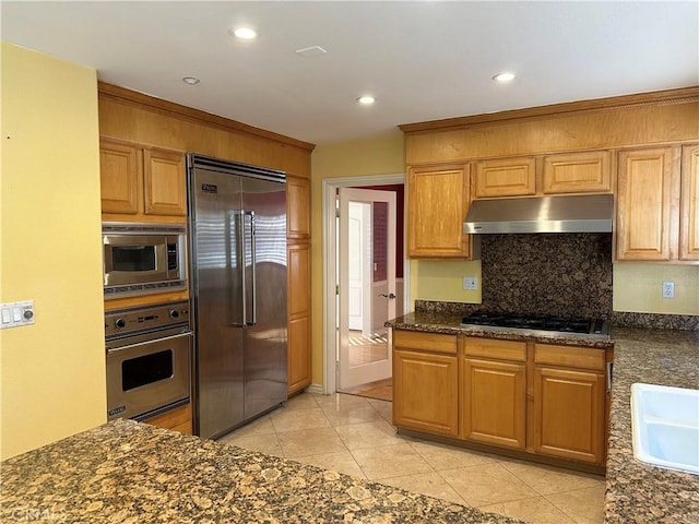 kitchen with built in appliances, light tile patterned floors, recessed lighting, under cabinet range hood, and decorative backsplash