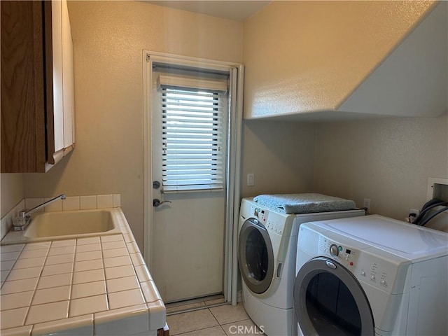 laundry room featuring light tile patterned floors, washing machine and clothes dryer, a sink, and cabinet space