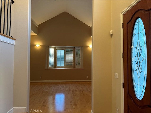 foyer entrance featuring lofted ceiling, wood finished floors, and baseboards