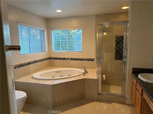 bathroom with toilet, a tub with jets, vanity, a shower stall, and recessed lighting