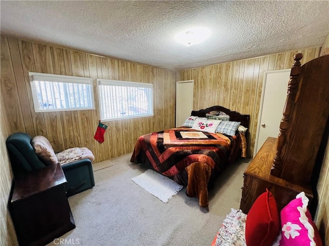 bedroom with a textured ceiling, carpet, and wooden walls