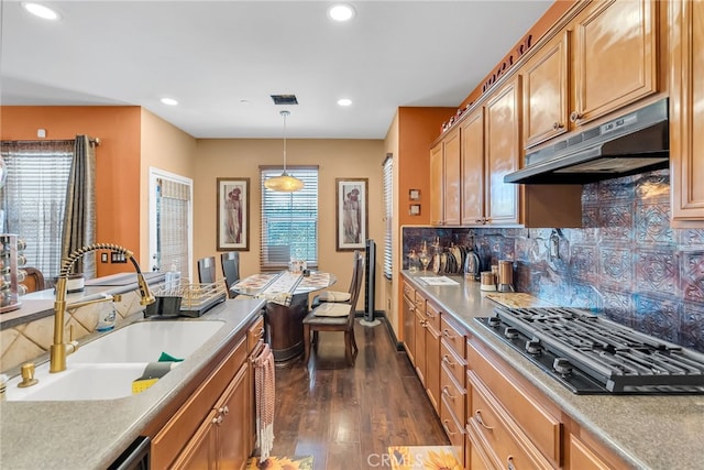 kitchen featuring black gas stovetop, under cabinet range hood, dark wood-type flooring, a sink, and plenty of natural light