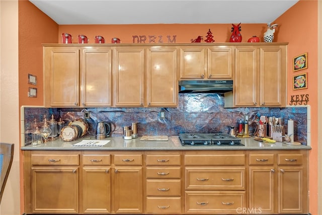 kitchen featuring light countertops, backsplash, light brown cabinets, gas cooktop, and under cabinet range hood