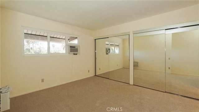 unfurnished bedroom featuring carpet flooring, radiator heating unit, and two closets